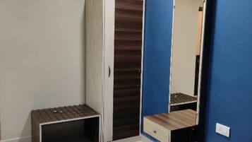 A bedroom with a wardrobe, a bedside table, a mirror, and a bed.
