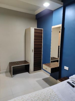 Un dormitorio con armario, mesita de noche, espejo y cama.
