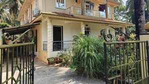 Ein zweistöckiges Haus mit Balkon, umgeben von tropischer Vegetation.