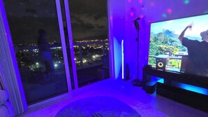 A room with a large window overlooking a cityscape at night, a television on a stand, and a floor lamp. - Luxury penthouse 1-bedroom By Miami river amazing view, parking, Gym & Pool (Miami)