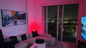 A modern living room with a sectional sofa, a white coffee table, and a large window overlooking a cityscape at night. - Luxury penthouse 1-bedroom By Miami river amazing view, parking, Gym & Pool (Miami)