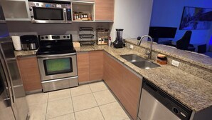 A modern kitchen with stainless steel appliances, wooden cabinets, a granite countertop, and a blue-lit wall. - Luxury penthouse 1-bedroom By Miami river amazing view, parking, Gym & Pool (Miami)