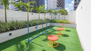 A rooftop garden with artificial grass, palm trees, and outdoor seating. - Studio w/ Self Check-in in Goiania Liu1606 (Goiânia)