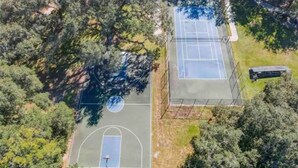 An aerial view of a tennis court surrounded by dense trees. - Updated Family Retreat in Gated Resort Community - Pool, Gym, Near Parks & MCO (Kissimmee)