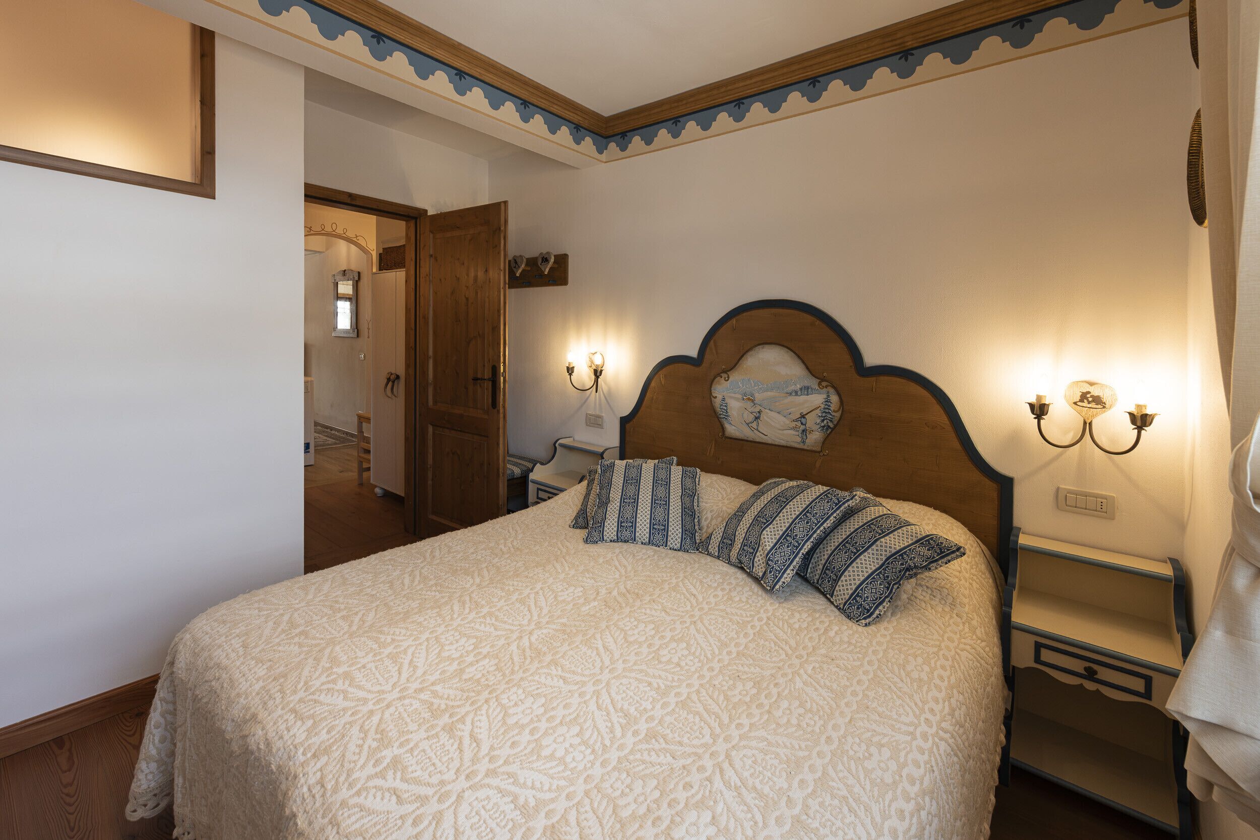 A bedroom with a large bed, a wooden headboard, bedside lamps, and a nightstand.