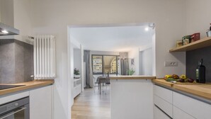 Una cocina moderna con armarios blancos, una encimera de madera y vistas a un comedor.