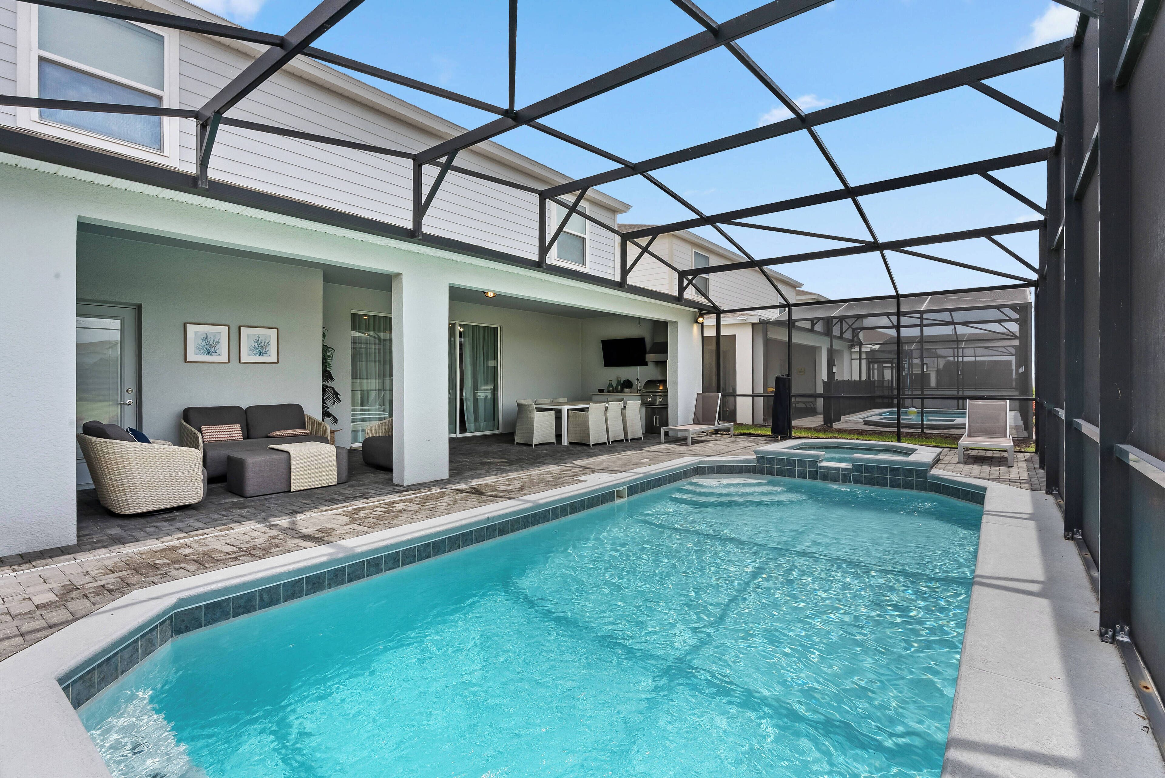 Una piscina interior con un patio cubierto, sillas de descanso y un televisor.