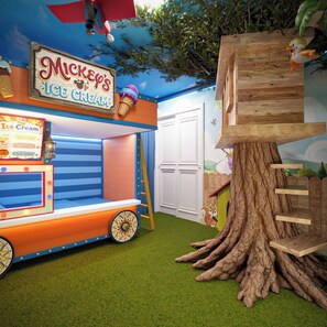 Ein Eisstand von Mickey's mit einem Schild, eine hölzerne Baumhütte mit einem Eichhörnchen und ein blauer Himmel als Hintergrund.