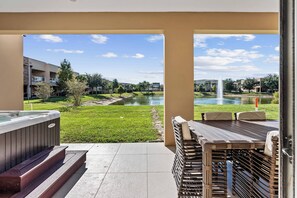 Eine Terrasse mit Whirlpool, Sitzgelegenheiten im Freien und Blick auf einen Fluss und Gebäude.