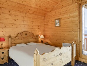 A wooden cabin bedroom with a bed, nightstands, a lamp, and a framed picture on the wall. - Spacious chalet in Bisanne 1500 with WIFI and stunning view (Villard-sur-Doron)