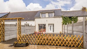 Une cour arrière clôturée, agrémentée d’une pergola en bois, d’une table de patio et de plantes en pot.
