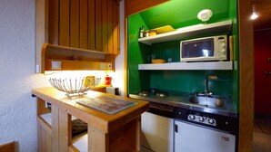 A compact kitchen with wooden cabinets, a microwave, and a sink. - Ski-in duplex for 6 in Arc 1800, southeast balcony (Les Arcs 1800)