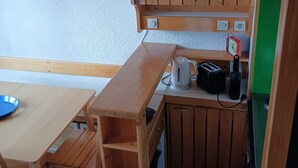 A compact kitchen with wooden cabinets, a countertop, a kettle, a toaster, and a clock. - Ski-in duplex for 6 in Arc 1800, southeast balcony (Les Arcs 1800)