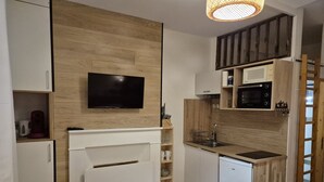A modern kitchen with a built-in microwave, a dishwasher, and a TV mounted on the wall. - Cozy 17m² studio, near cable car, 2/4 pers, parking (Cauterets)