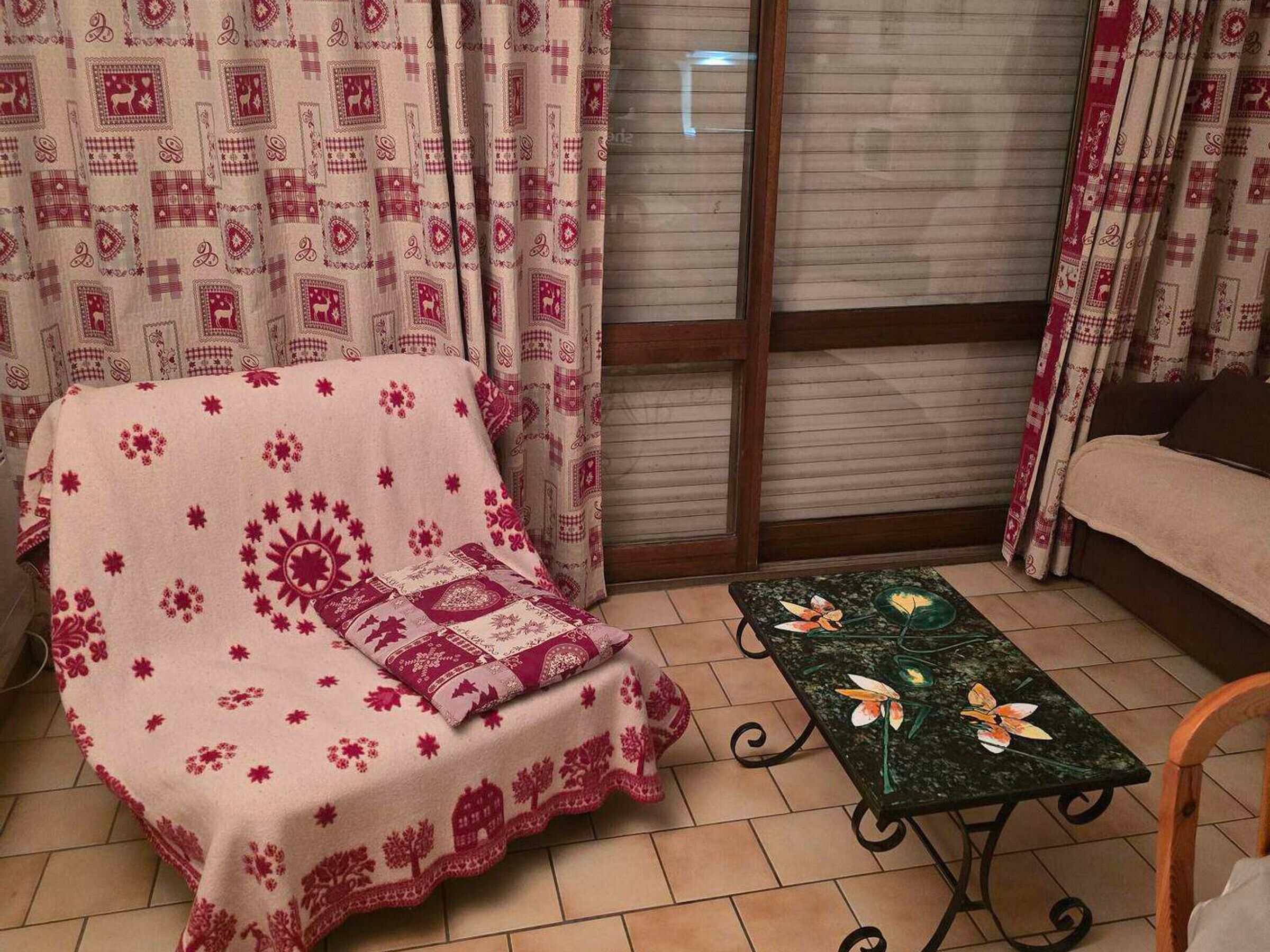 Una sala de estar acogedora con un sofá cubierto por un plaid estampado, una mesita con diseño floral y cortinas de estampado geométrico.