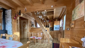 Ein Holzblockhaus-Interieur mit Essbereich, Küche und Treppe.