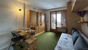 Un espace de vie compact comprenant un coin repas, un canapé, une échelle et une vue sur l’extérieur.