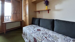Une pièce avec un lit, une armoire en bois et une fenêtre.