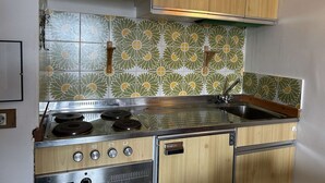 Une cuisine de taille réduite, dotée d’une cuisinière à gaz, de meubles en bois et d’un crédence décorée.