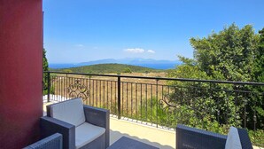 Ein Balkon mit Korbmöbeln und Blick auf die Landschaft.
