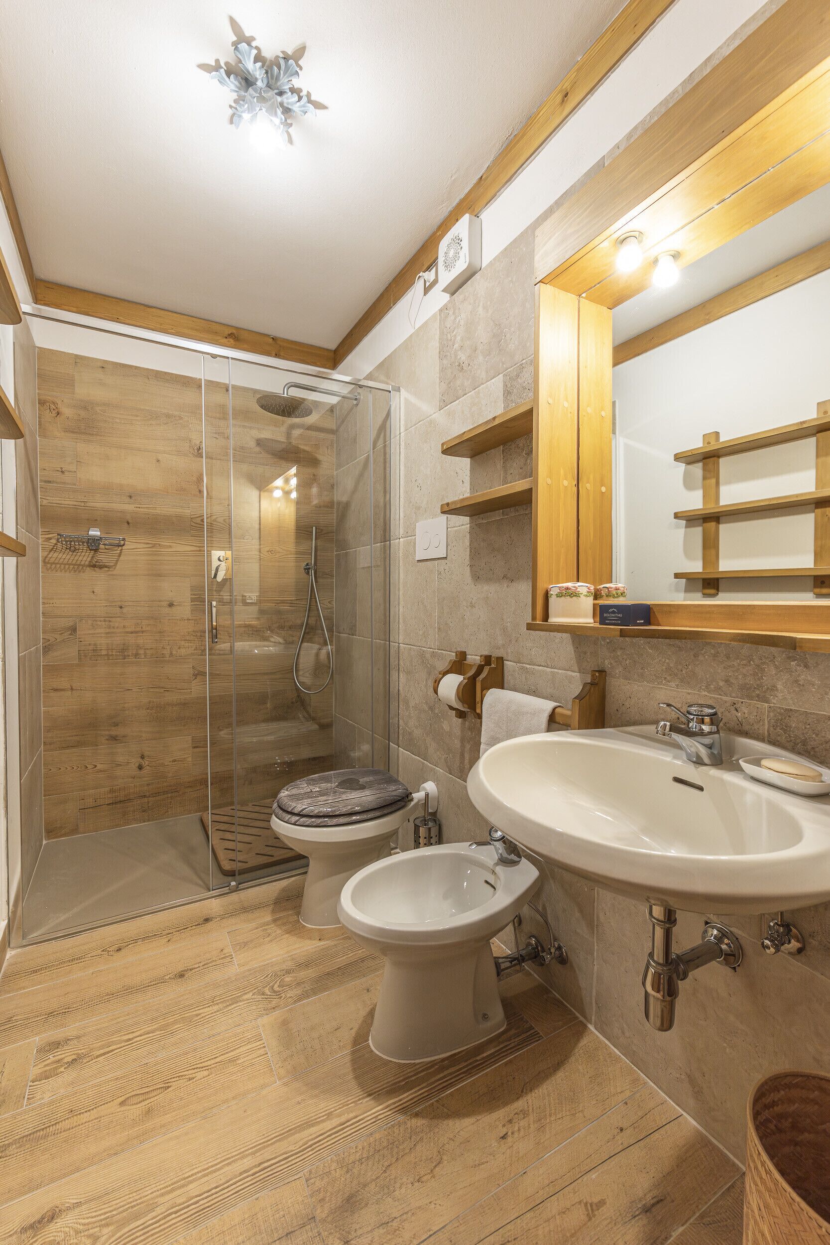 A modern bathroom with a glass-enclosed shower, a freestanding toilet, and a sink with a mirror above.