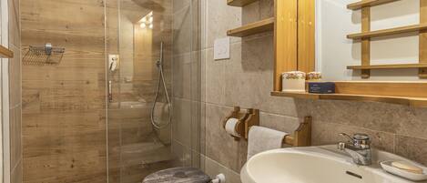 A modern bathroom with a glass-enclosed shower, a freestanding toilet, and a sink with a mirror above.
