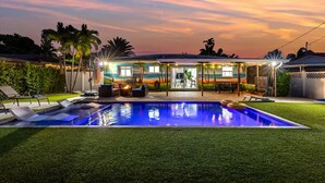 Patio con piscina, mobiliario exterior y una casa con un mural de playa.