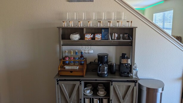 A coffee station with a coffee maker, mugs, and a display of hot cocoa. - Candle Maker's Cove: King Bed, Fiber WiFi, Full Kitchen Access (Leander)