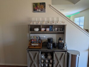 A coffee station with a coffee maker, mugs, and a display of hot cocoa.