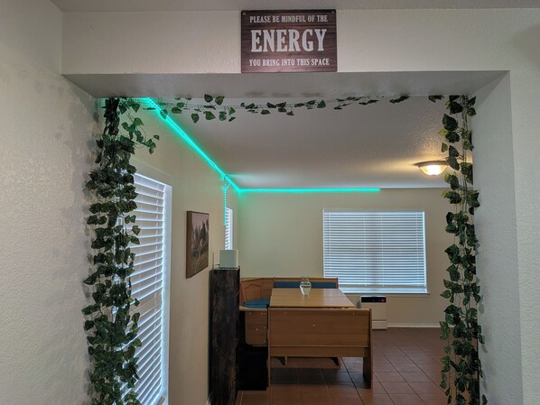 A room with a dining table, chairs, a ceiling light, and a sign on the wall.