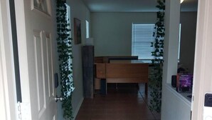 A hallway with a blue carpet leading to a room with a desk and a chair. There is a sign on the wall that reads "Please be mindful of the energy you bring into this space." - Candle Maker's Cove: King Bed, Fiber WiFi, Full Kitchen Access (Leander)