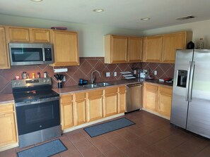 A modern kitchen with wooden cabinets, stainless steel appliances, and a tiled backsplash.
