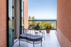 A balcony with a metal chair, potted plants, and a view of the sea. - Apartment 'Terrazzo Eucalipto' with Sea View, Wi-Fi and Air Conditioning (Cefalù)