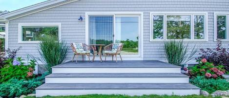 A residential house with a front porch, a sliding glass door, and a small patio area with outdoor furniture.
