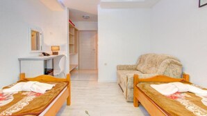 A room with two wooden beds, a small desk, a chair, and a large armchair. - Glory Sanctuary Retreat (Citluk)