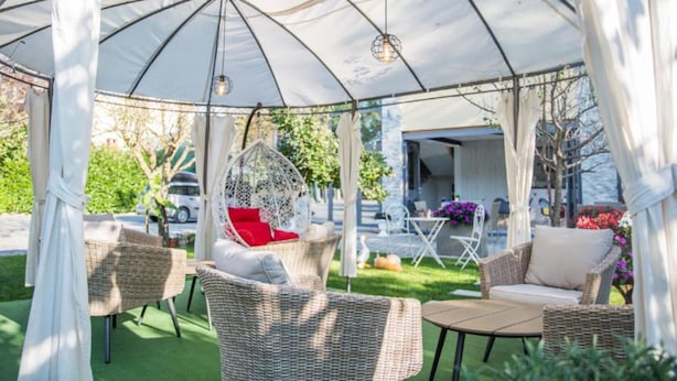 A covered outdoor seating area with wicker furniture and a hanging light fixture. - Glory Sanctuary Retreat (Citluk)