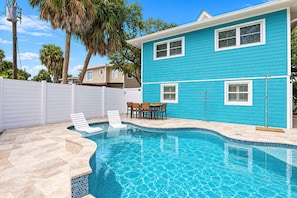 A residential swimming pool with a tiled deck, a white fence, and a blue house in the background. - 🏝️Walk to Beach | Great Outdoor Space | Pet Friendly | Sand Dollar Suite🏝️ (Fort Myers Beach)
