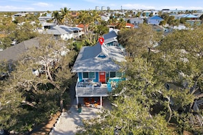 A two-story house with a red door, a balcony, and a view of the surrounding neighborhood. - 🏝️Walk to Beach | Great Outdoor Space | Pet Friendly | Sand Dollar Suite🏝️ (Fort Myers Beach)