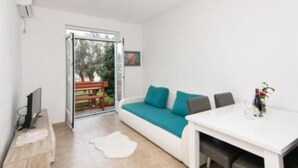 A modern room with a white sofa, a small table, and a TV. - Apartments Savić Near the Sea (Denovici)