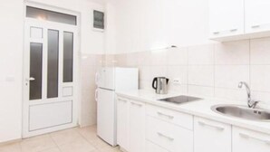 A small, white kitchen with a refrigerator, a kettle, and a sink. - Apartments Savić Near the Sea (Denovici)