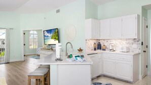 Uma cozinha moderna com armários brancos, painel de parede em mármore e uma ilha central com banquetas.