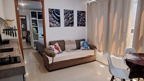 Una sala de estar moderna con un sofá, una mesa de comedor con sillas y una zona de cocina con mostrador y fregadero.