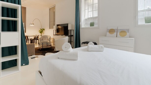 Ein Hotelzimmer mit Bett, Schreibtisch, Stuhl, Fernseher und Fenster.