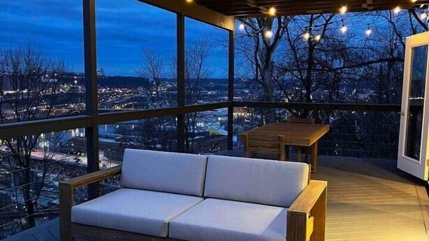 Une terrasse extérieure avec un foyer, un canapé et des guirlandes lumineuses.
