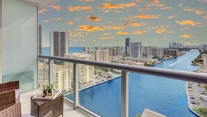 A balcony with a cityscape view, a glass railing, and a table with bottles. - Upper Studio w/ Private Balcony + Fitness Center (Hallandale Beach)