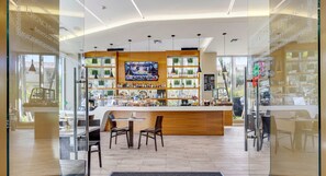 A modern bar area with a counter, seating, and a television screen. - Upper studio w/ Private Balcony + Pool + Gym (Hallandale Beach)