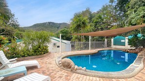 A swimming pool with a brick deck, lounge chairs, and a view of hills. - Magnetic Reef 5 (Arcadia)