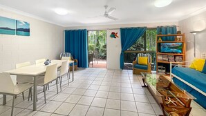 A room with a dining table, chairs, a sofa, a TV, and a bookshelf. - Magnetic Reef 5 (Arcadia)