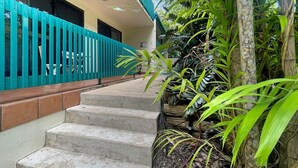 A staircase leading to a balcony with a blue railing, surrounded by lush greenery. - Magnetic Reef 5 (Arcadia)