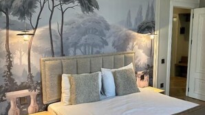 A bedroom with a bed, a nightstand, a wall mural, and an air conditioning unit. - Luxury apartments by city (Baku)